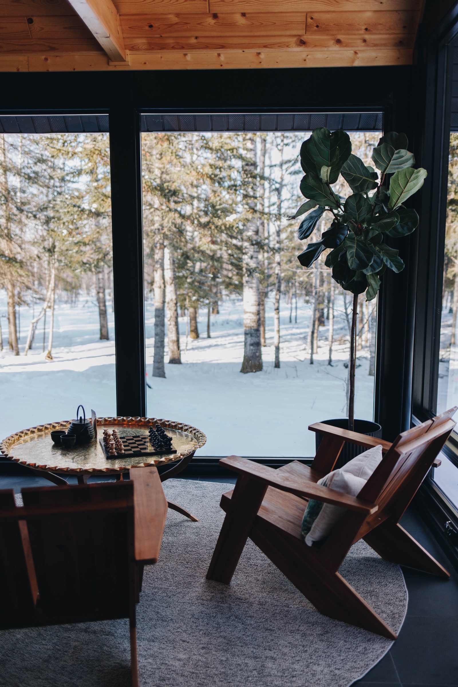 Relaxation lounge with chess set, leather chairs, and floor-to-ceiling windows overlooking snowy birch forest
