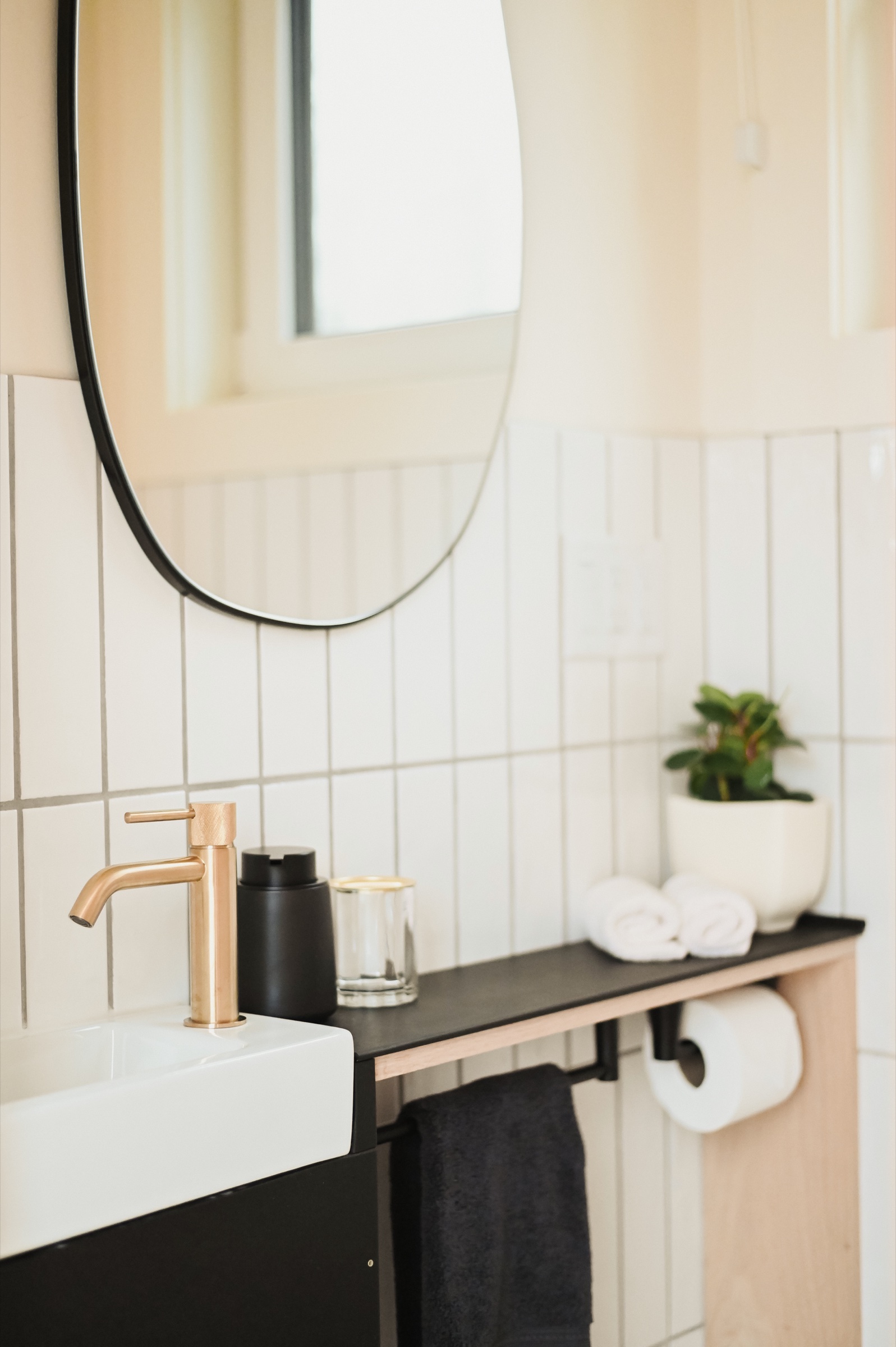 Bathroom vanity with brass fixtures and vertical tile
