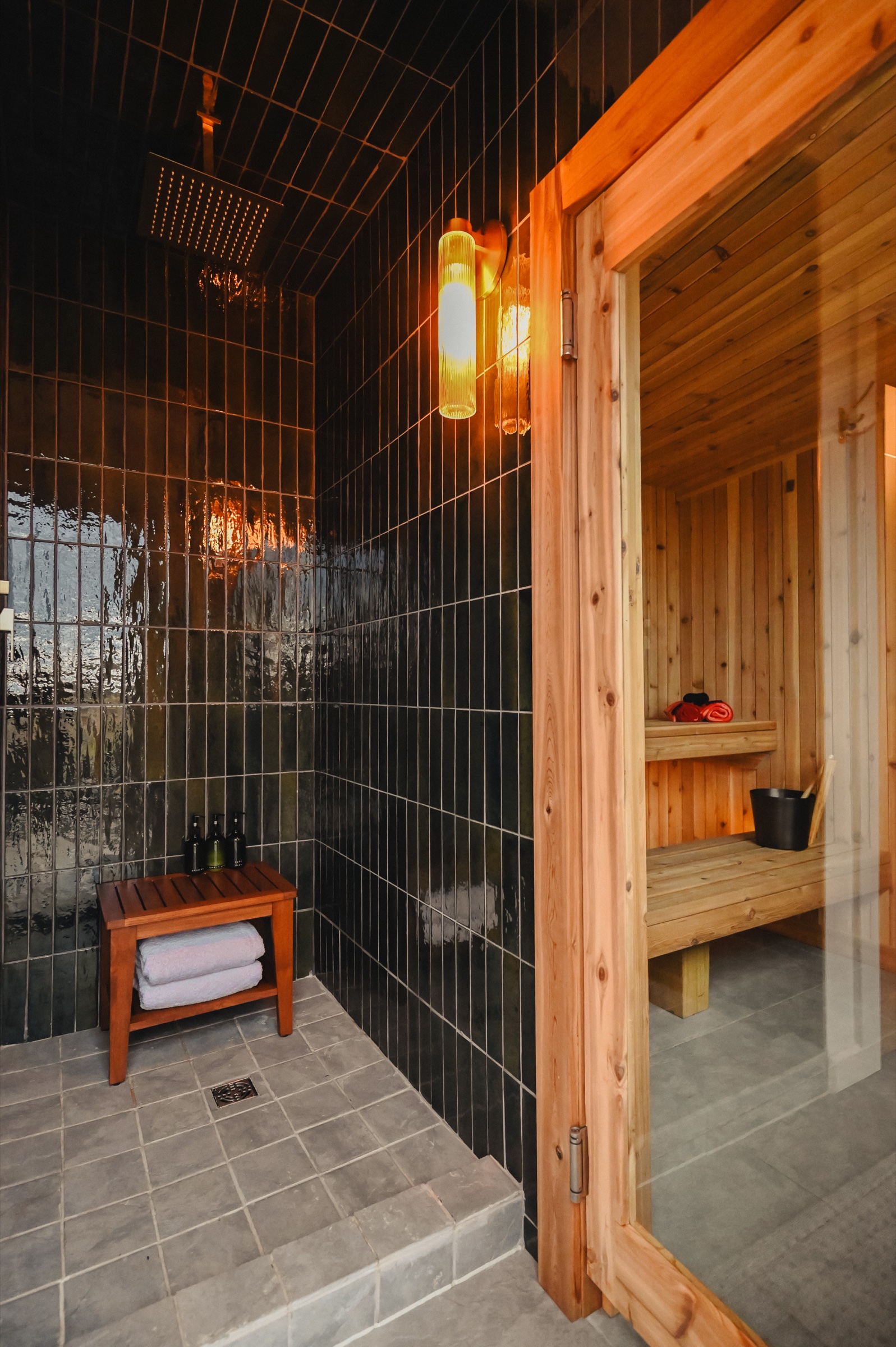 Dark tile shower room with amber lighting and sauna entry